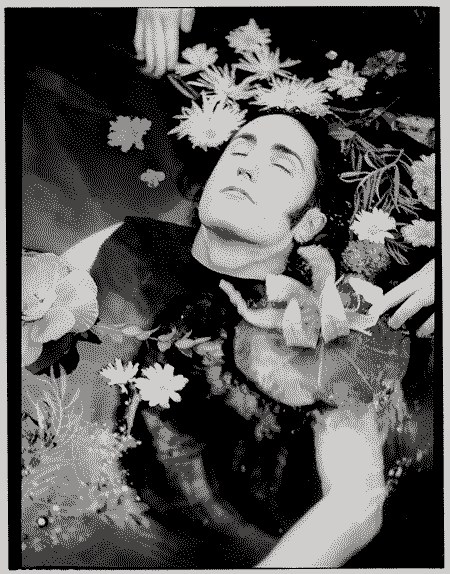 fotografía del músico Trent Reznor en 1994 recostado sobre el agua, donde su torso esta sumergido, pero su cabeza emerge del agua y la rodea varias flores